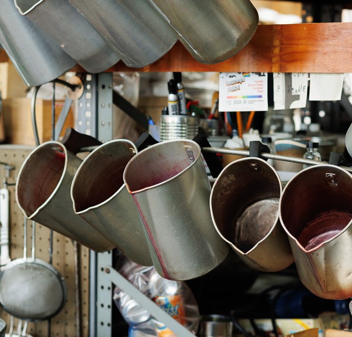 Waxman6142E-h680 Silver metal wax pitchers hanging on a rack in Waxman's studio.