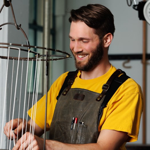 Waxman5885sq Waxman's head candle maker, Mitch, stands wicking a taper rack in Waxman's candle studio.